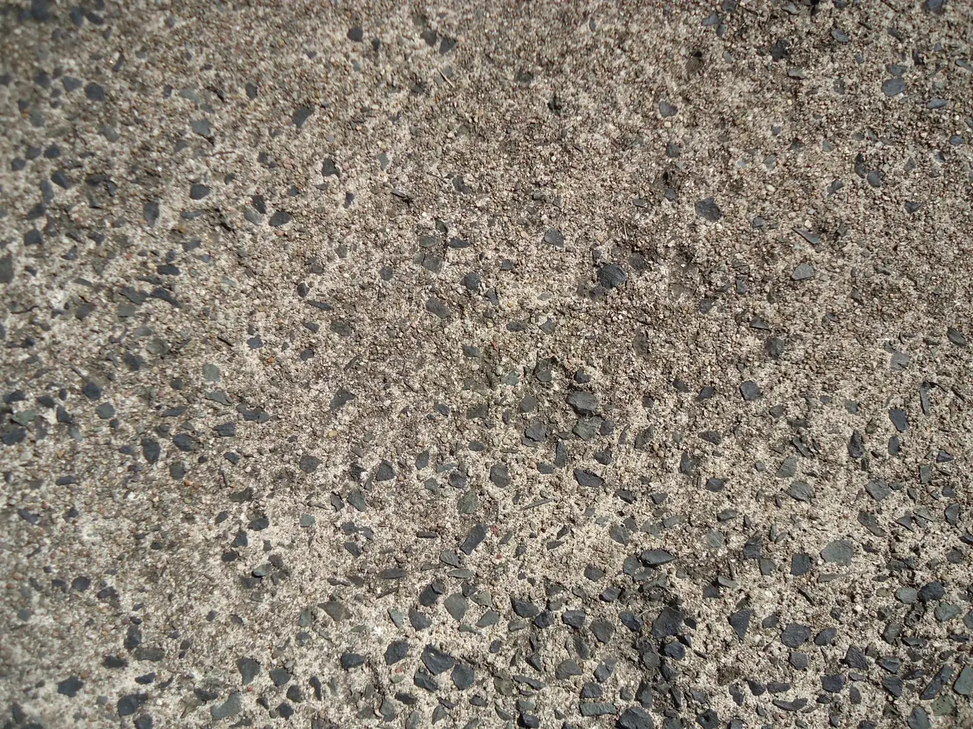 Exposed-aggregate concrete surface photographed in raking sunlight