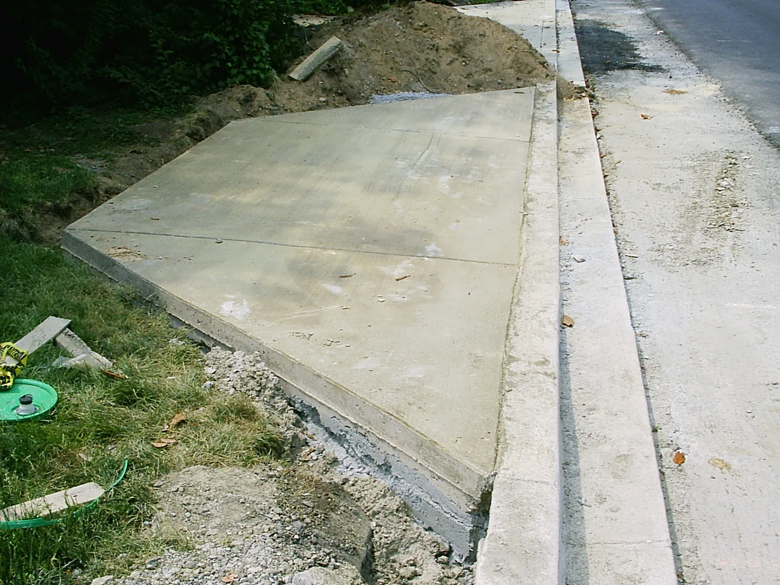 Freshly poured driveway apron meeting a sloped street curb and gutter