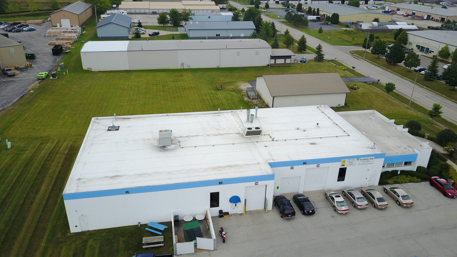 Aerial view of an industrial building with a white flat membrane roof and blue trim