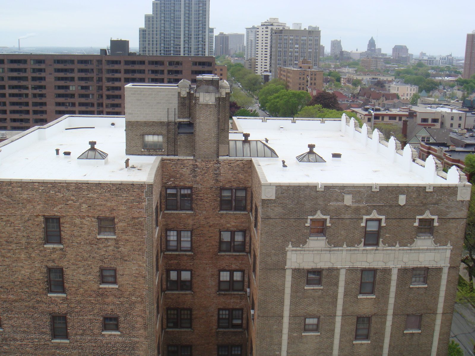 White flat roof on a brick apartment building with skylights and the Milwaukee skyline behind