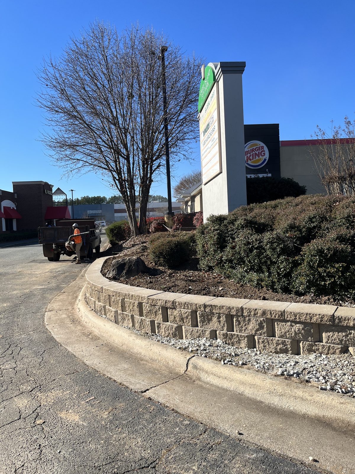 Block retaining wall curving along a planted bed on a commercial property